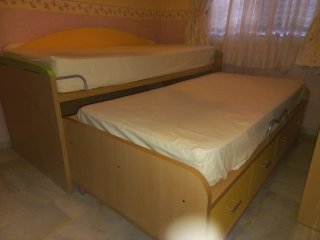 Dormitorio juvenil con cama nido y estanterías.