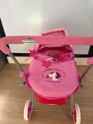 Cochecito de juguete rosa con unicornio
