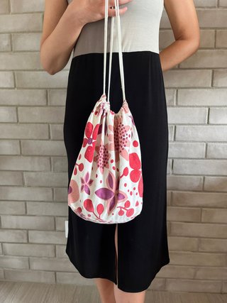 Bolso blanco tipo saco con estampado de flores.
