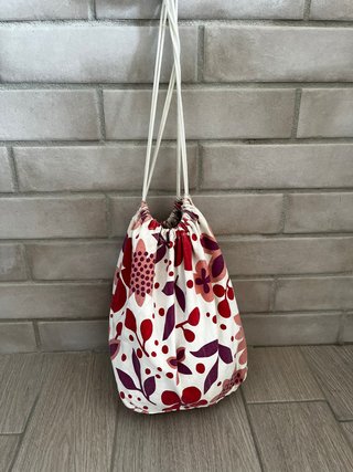 Bolso blanco tipo saco con estampado de flores.