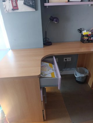 Escritorio de madera con cajonera y estantería.