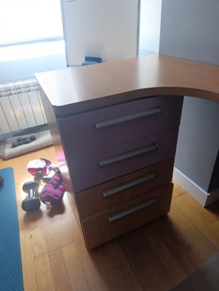 Escritorio de madera con cajonera y estantería.