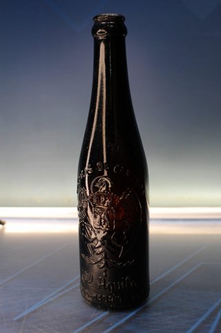 Botella antigua El Águila, ambar, con relieve.