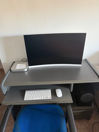 Escritorio gris con silla azul y altavoces