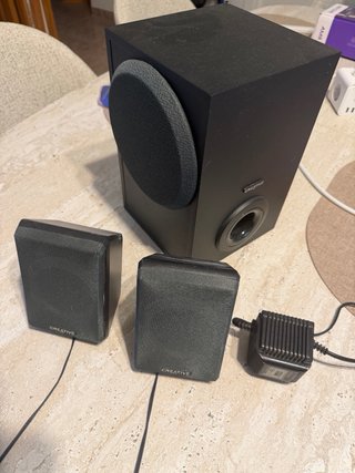 Escritorio gris con silla azul y altavoces
