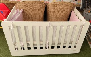 Cuna de bebé blanca con protector rosa