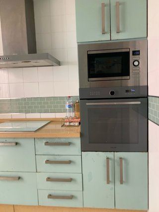 Cocina completa con muebles, encimera, campana y 2