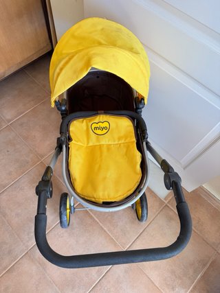Carrito de bebé Miyo con accesorios y dos bebés.