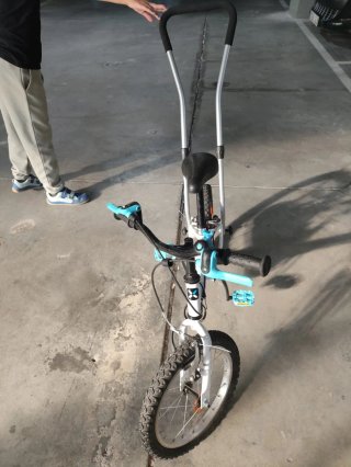 Bicicleta infantil con barra de aprendizaje.