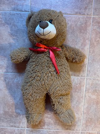 Oso de peluche marrón con lazo rojo