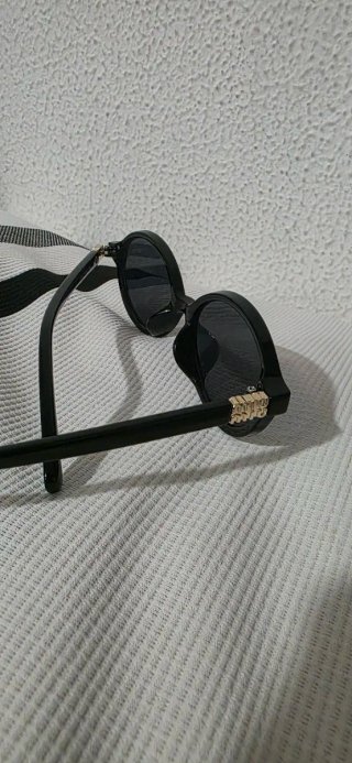 Gafas de sol ovaladas negras con detalles dorados