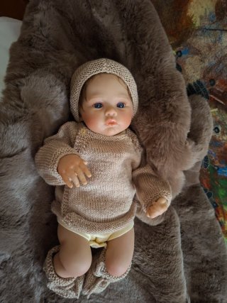 Muñeca realista con chupete y muchos complementos.