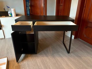 Escritorio IKEA oscuro con cajones y almacenaje.