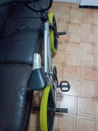 Bicicleta BMX plateada con ruedas verdes