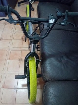 Bicicleta BMX plateada con ruedas verdes