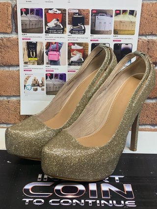 Zapatos de tacón dorados de exposición