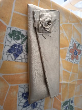 Bolso de mano dorado con flor