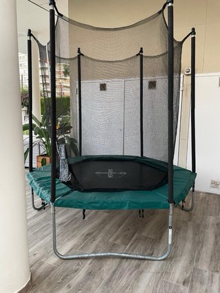 Cama elástica verde con red de seguridad