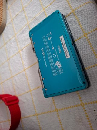 Nintendo 3DS Aqua con caricatore e piattaforma.