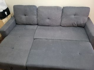 Sofá cama gris  y mesa con mueble de comedor