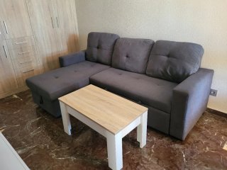 Sofá cama gris  y mesa con mueble de comedor
