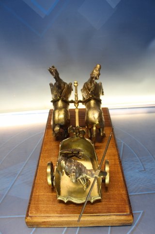 Escultura en bronce, Gladiador, guerrero romano en viga. Carro tirado por dos caballos.