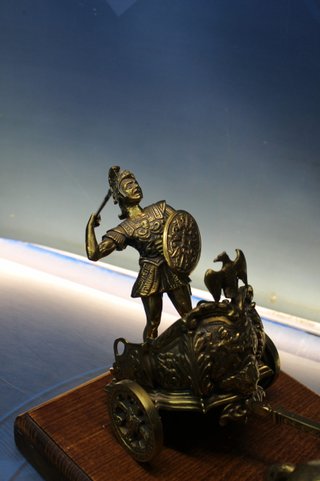Escultura en bronce, Gladiador, guerrero romano en viga. Carro tirado por dos caballos.
