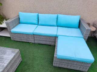 Sillón exterior con cojín azul y mesa con cristal.