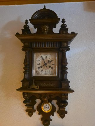 Reloj de pared antiguo de madera con péndulo.