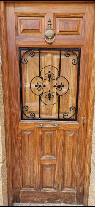 Puerta de madera con reja decorativa