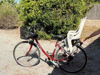 Bicicleta roja con silla para niño y casco adulto