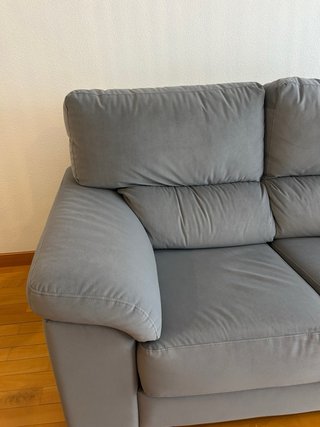 Sofá gris biplaza de tela con asientos extraíbles.