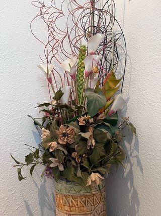 Jarrón alto con flores secas y ramas decorativas.