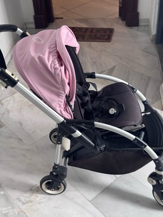 Carro de bebé negro con capota rosa.