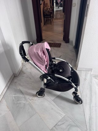 Carro de bebé negro con capota rosa.