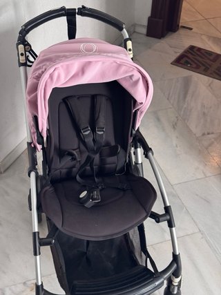 Carro de bebé negro con capota rosa.