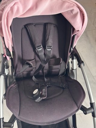 Carro de bebé negro con capota rosa.