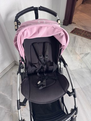 Carro de bebé negro con capota rosa.