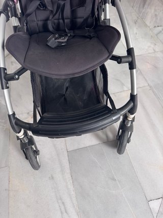 Carro de bebé negro con capota rosa.