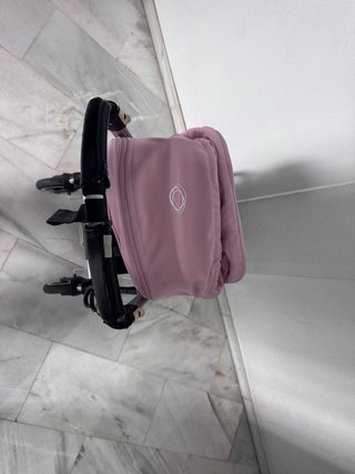 Carro de bebé negro con capota rosa.