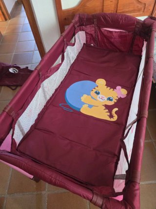 Cuna de viaje plegable rosa con dos alturas.