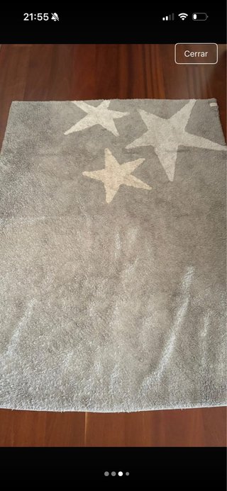 Alfombra gris con estrellas de colores palidos.