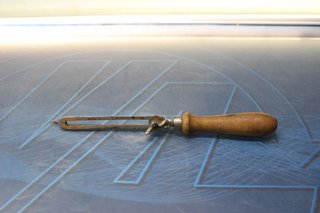 Antiguo abrelatas con mango de madera.