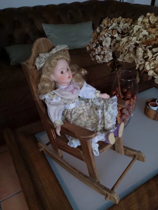 Muñeca de porcelana en mecedora