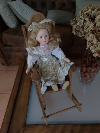 Muñeca de porcelana en mecedora
