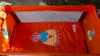 Cuna de viaje naranja con dibujos