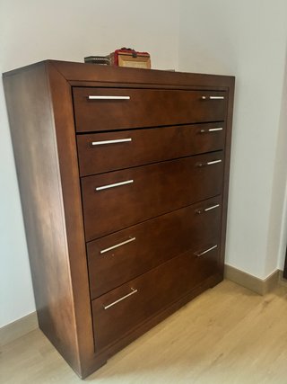Cómoda de madera oscura con 5 cajones.