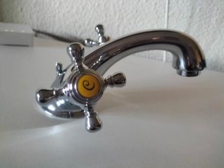 Grifo de lavabo plateado con detalle amarillo