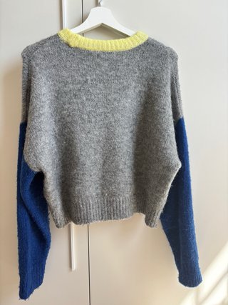 Jersey gris con cuello amarillo y mangas azules