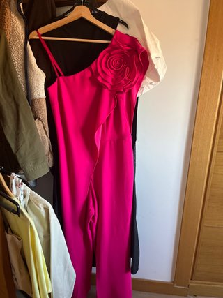 Mono rosa elegante con flor. Tiene el bajo cogido.